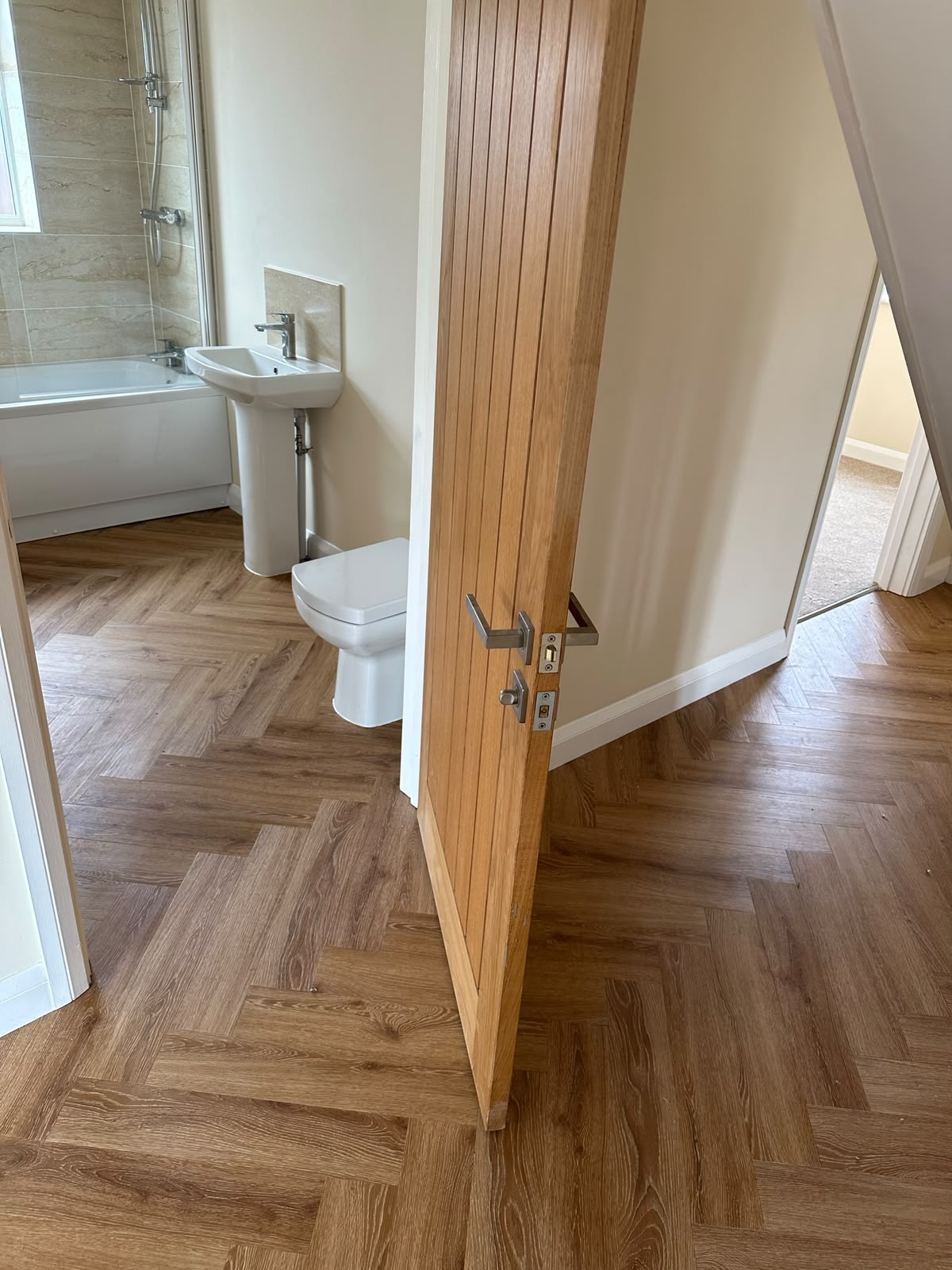 Herringbone LVT flooring running into a bathroom